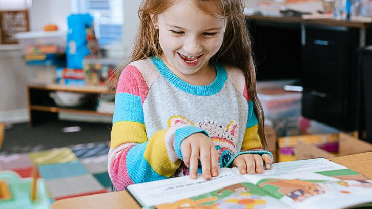 Little girl reading a Generous Family storybook in her room, Christian children’s book about kindness and compassion.