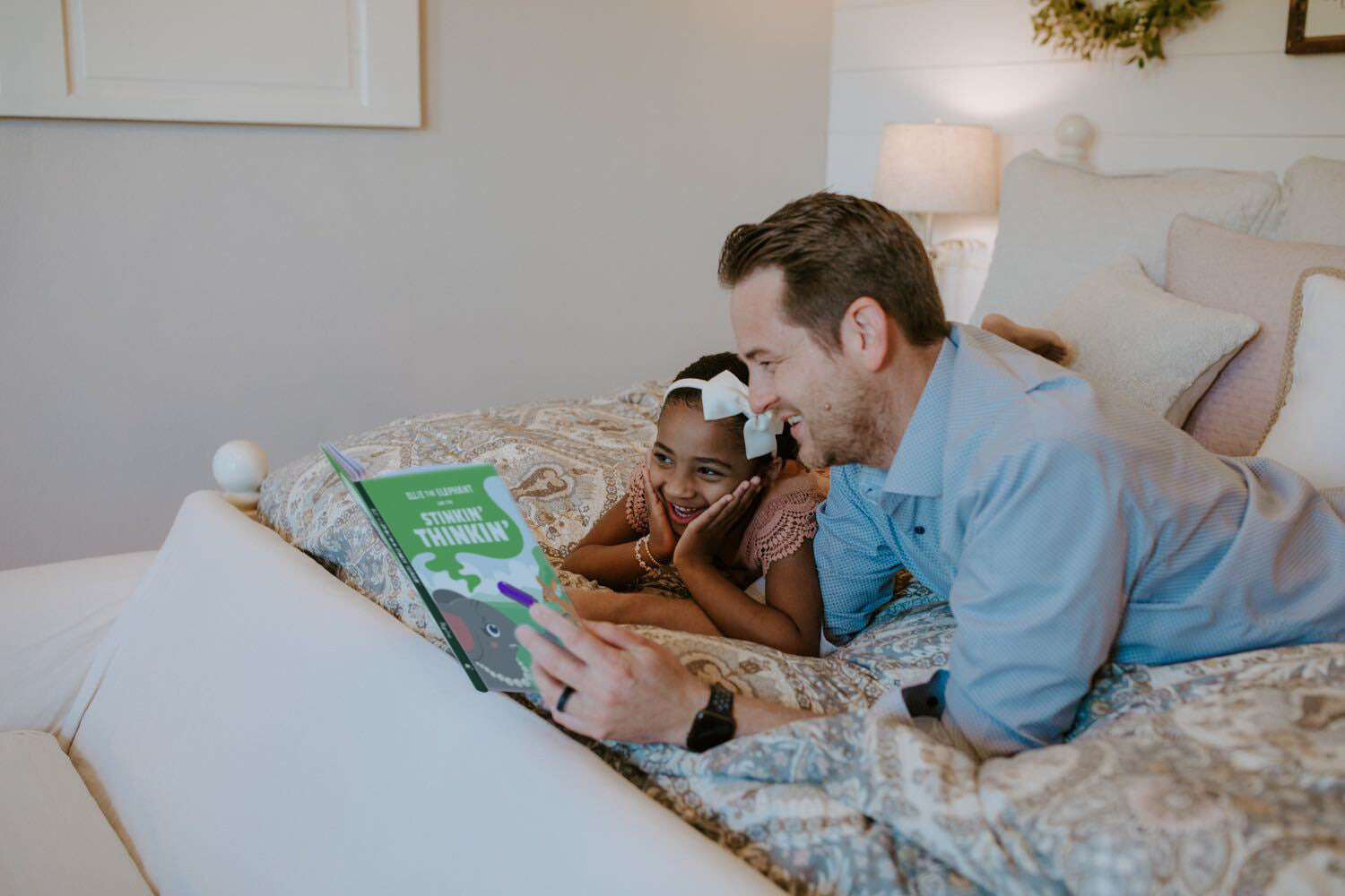 Dad reading with his daughter on the bed, teaching kids generosity through time together