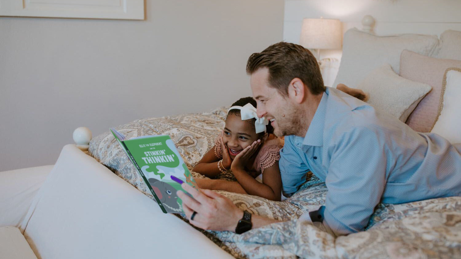 Dad reading with his daughter on the bed, teaching kids generosity through time together