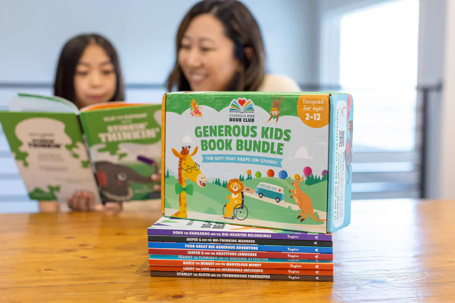 Generous Kids Book Bundle on a table while a mother and daughter read children’s books together in the background.