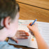 Child writing in a notebook with a pen